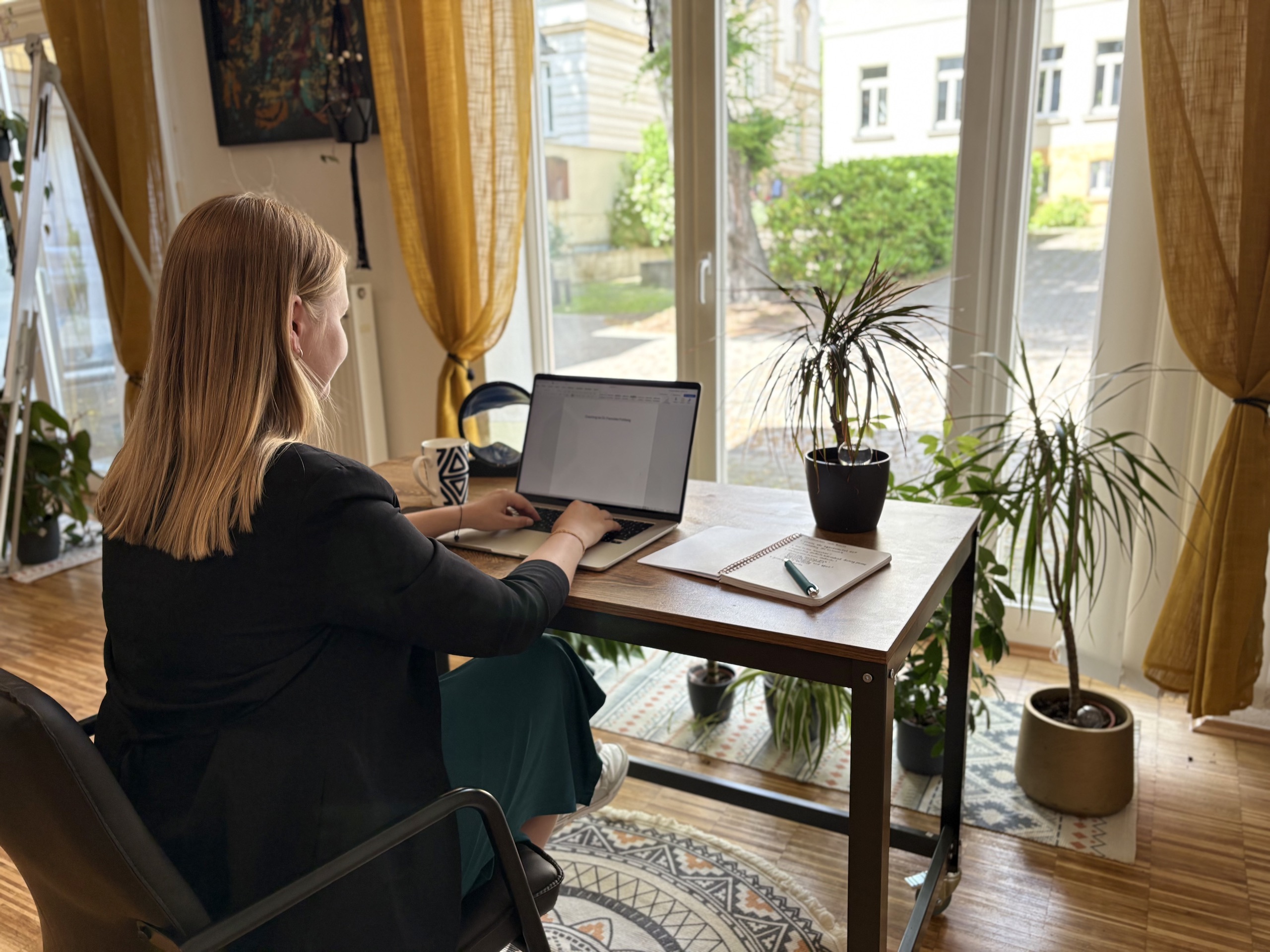 Franziska Frohberg an ihrem Schreibtisch mit Blick in den grünen Innenhof